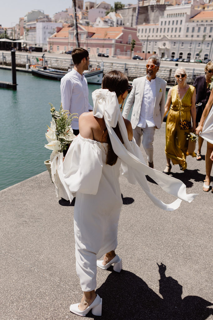Bride and wedding guests walking by the river in Lisbon