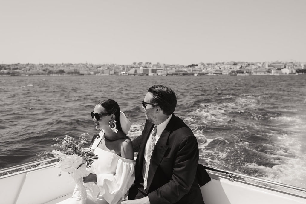 Bride and groom on the boat with a riverside view in Lisbon